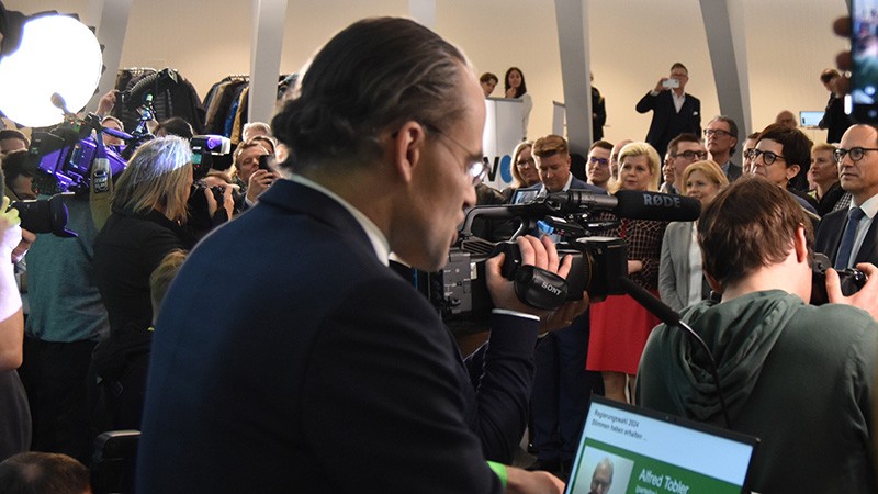 Staatssekretär Benedikt van Spyk gibt im gut besuchten Wahlzentrum im Pfalzkeller die Ergebnisse der Regierungswahl bekannt.